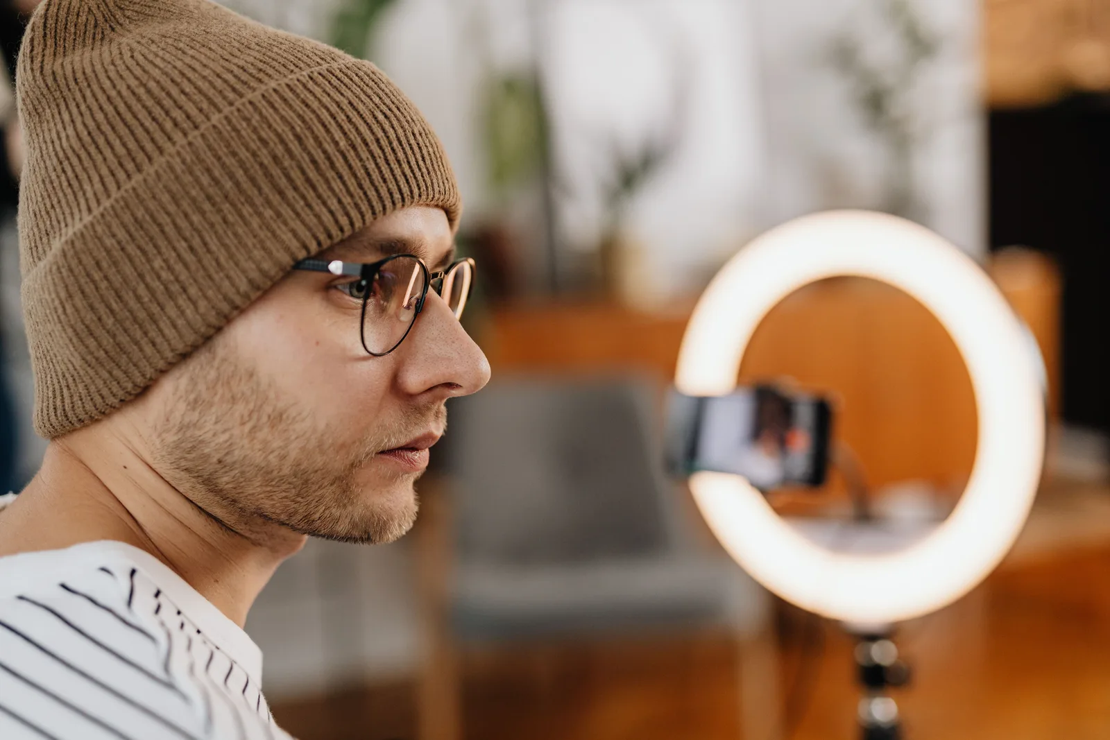 A man recording content for social media using a phone and ring light